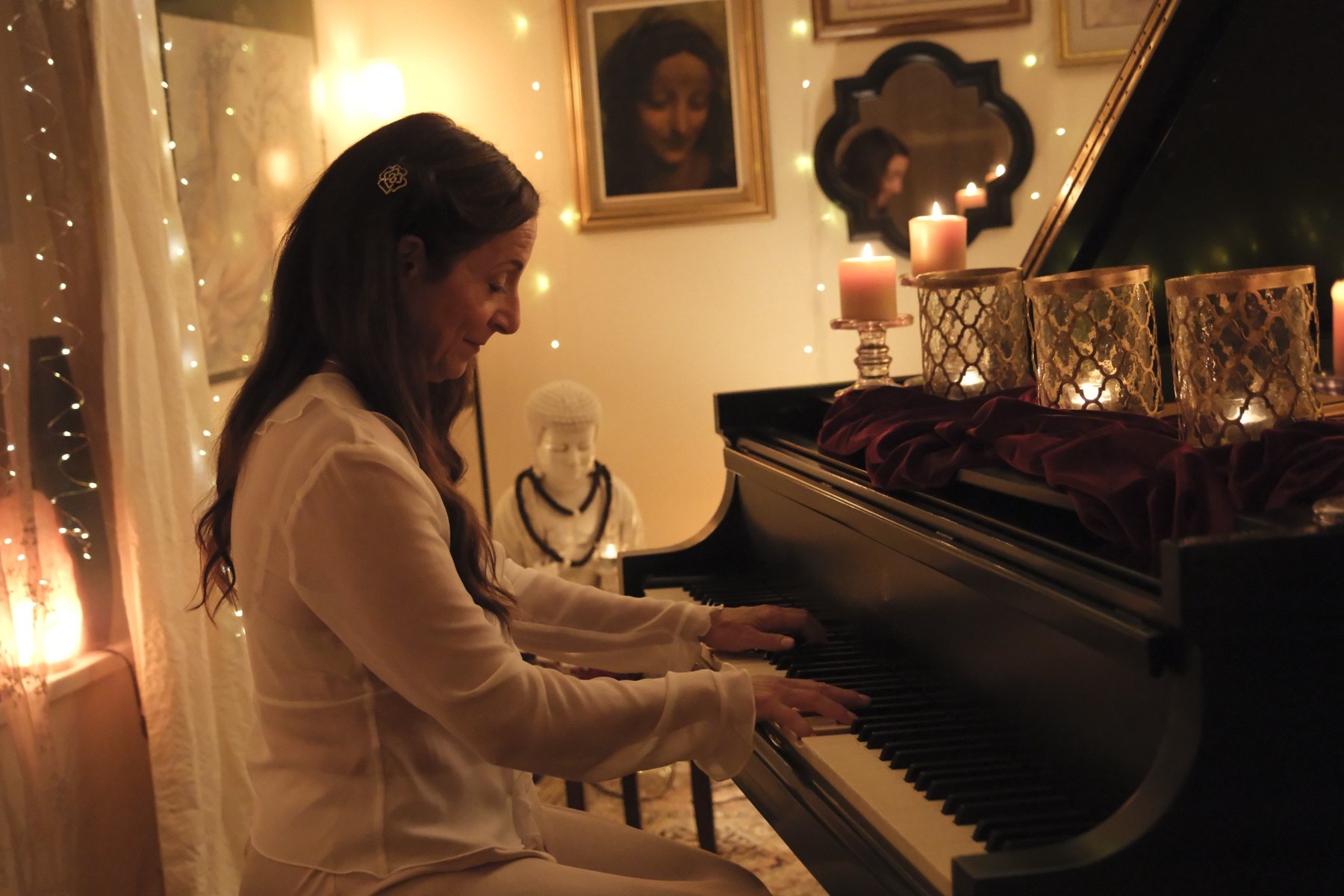 Lori-Ann Speed performing at the piano in her candlelit studio